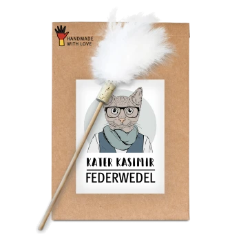Ein braunes Paket mit einer Cartoon-Katze in Brille und Schal, beschriftet mit "KATER KASIMIR FEDERWEDEL" und markiert mit "HANDMADE WITH LOVE", mit einem Feder-Spielzeug.