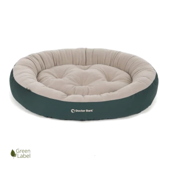 Rundes Haustierbett mit einem plüschigen beigen Zentrum und einem dunkelgrünen äußeren Rand, mit dem Logo "Doctor Bark" und einem "Green Label"-Symbol.