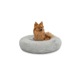 Ein flauschiger Pomeranian-Hund sitzt bequem in einem runden, weichen grauen Haustierbett auf einem weißen Hintergrund.