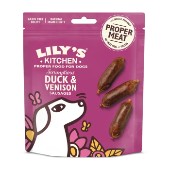 Emballage de nourriture pour chien Lily's Kitchen présentant des "Saucisses de canard et de venaison délicieuses," avec trois saucisses visibles, sur un fond violet.