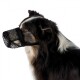Een zijprofiel van een zwart en bruin hond met een zwart gaas muilkorf, die zijn aandachtige uitdrukking en fluffy vacht toont.