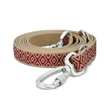 Boho-Chic Hundeleine June 2 m Eine gerollte Haustierleine mit einem beigen Stoff mit rotem Diamantmuster und einem silbernen Metallclip zur Befestigung.