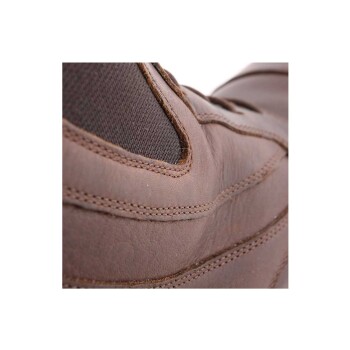 Nahaufnahme eines braunen Lederschuhs mit strukturierten Stoffpaneelen und sichtbaren Nähdetails.