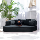 Ein schwarzes Hundebett mit plüschiger Textur, auf dem ein Dackel bequem ruht, umgeben von Zimmerpflanzen und natürlichem Licht.