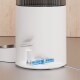 Nahaufnahme eines weißen Haustier-Wasserbrunnens mit einem transparenten Sockel, der blaue Batterien und interne Komponenten zeigt, auf einer Holzoberfläche platziert.