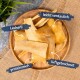 Ein Holzbrett mit verschiedenen Hundeleckerlis beschriftet: "Leckerli," "leicht verdaulich," "proteinreich," und "luftgetrocknet."