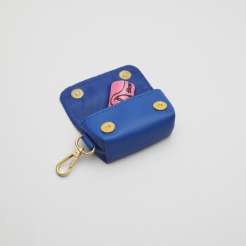 Blauer Haustierabfallbeutelspender mit einer rosa Rolle Beutel darin, mit goldenen Druckknöpfen und einem Metallclip zur Befestigung.