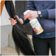 Person hält eine Flasche Stiefel Top Shine Aloe Vera Pflegespray und einen schwarzen Pferdeschweif.