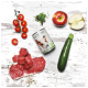 Frische Hundefutterzutaten: rohes Rindfleisch, Kirschtomaten, Zucchini, ein Apfel und eine Dose "DOG'S LOVE" auf einer Holzoberfläche.