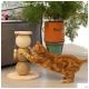 Un chat orange joueur s'étire vers un griffoir à trois niveaux en fibres naturelles, avec un jouet en plumes suspendu.