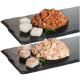 Zwei Portionen Tierfutter auf schwarzem Schiefer: eine mit gewürfeltem Fleisch in Sauce, die andere mit cremigen Fleischstücken und Rosmarin-Garnitur.