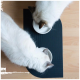 Zwei weiße Katzen mit dunklen Ohren, die aus weißen Schalen auf einer schwarzen Fütterungsmatte fressen, von oben betrachtet.