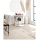 Zwei verspielte Kätzchen, eines oben sitzend und das andere, das aus einem gemütlichen grauen Katzenbaum herauslugt, in einem modernen Wohnzimmer.