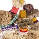 Eine bunte Auswahl an Haustierspielzeugen aus natürlichen Materialien, darunter Holzblöcke, geflochtenes Gras und zerrissenes Papier, spielerisch angeordnet.