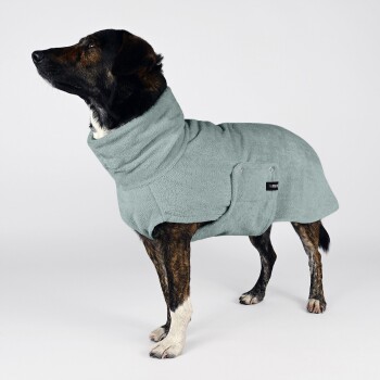 Ein brauner und schwarzer Hund, eingewickelt in ein weiches, hellblaues Handtuch, das von der Kamera abgewandt ist, vor einem schlichten weißen Hintergrund.