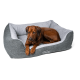 Ein brauner Hund, der bequem in einem plüschigen, grauen Haustierbett mit weißem Innenraum ruht, mit einem stilvollen Design und weichem Stoff.