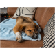 Ein entspannter Hund, der auf einer weichen blauen Decke auf einem braunen Sofa liegt, mit dekorativen Kissen im Hintergrund.