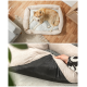 Ein hellbrauner Hund ruht auf einem plüschigen Hundebett mit einem grauen strukturierten Kissen, umgeben von einer gemütlichen Wohnzimmereinrichtung.
