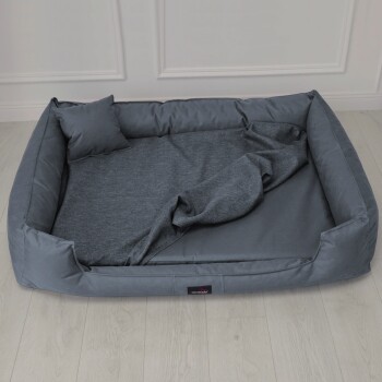 Ein elegantes graues Hundebett mit einem bequemen Design, auf dem ein Hund entspannt. Das Bett hat ein kleines Etikett mit der Aufschrift 'tierlando'.