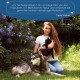 Eine Frau hält eine schwarze Katze neben einem großen Hund in einem Garten mit lila Blumen. Der Text darüber bewirbt Wolfsbacher Naturprodukte. Unterschrieben von Lena Huber.