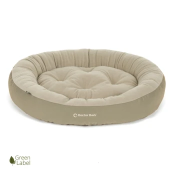 Rundes, plüschiges Hundebett in hellem Beige mit gestepptem Design, mit dem Logo 'Doctor Bark' und einem 'Green Label'-Symbol.