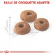Trois croquettes rondes pour animaux avec un trou au centre, affichées sur un croquis léger, avec le texte "TAILLE DE CROQUETTE ADAPTÉE" au-dessus.