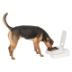 Ein Hund mit einem schwarz-braunen Fell frisst aus einem modernen weißen Futterspender mit offenem Deckel, der Trockenfutter zeigt.