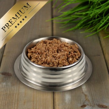 Eine Edelstahlschüssel für Haustiere, gefüllt mit texturiertem Nassfutter für Katzen, auf Holz mit grünem Gras im Hintergrund.