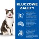 Zabawny kot z obrożą liże wargi obok tekstu o niskokalorycznej, wysokobiałkowej karmie z błonnikiem i tauryną dla zdrowia.