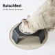 Eine flauschige weiße Katze, die aus einer modernen erhöhten Schüssel mit schwarzem Boden und beigem Tablett frisst, auf dem steht: "Rutschfest schützt Boden & Nerven."