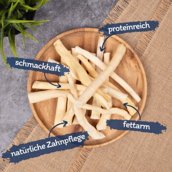 Ein Holzbrett hält weiße Hundekauartikel, die auf Deutsch beschriftet sind: "lecker", "reich an Protein", "fettarm" und "natürliche Zahnpflege."