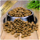 Eine silberne Futterschüssel für Haustiere, die überquillt mit runden, braunen Kroketten, von denen einige auf einer Holzoberfläche verstreut sind; ein 'PREMIUM'-Etikett in der Ecke.