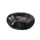Eine graue getigerte Katze, die friedlich in einem runden, flauschigen schwarzen Haustierbett schläft.