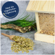 Holz-Vogelfutterspender mit grünem Vogelfutter in einer Schaufel, umgeben von Gras und Treibholz; Text: "Ideal als Vogelfutter-Ergänzung."