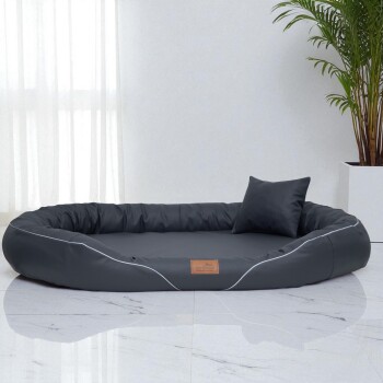 Schwarzes ovales Haustierbett mit erhöhten Rändern und passendem Kissen auf einem Marmorboden, beschriftet mit „tierlando“.
