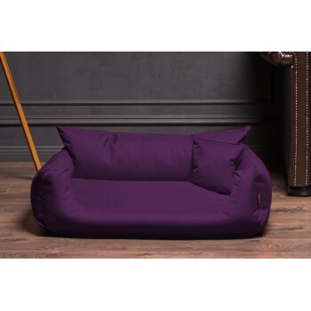 Lila Haustierbett mit weichen Kissen, auf Holzboden vor einer dunklen Wand platziert, ideal für kleine Hunde oder Katzen.