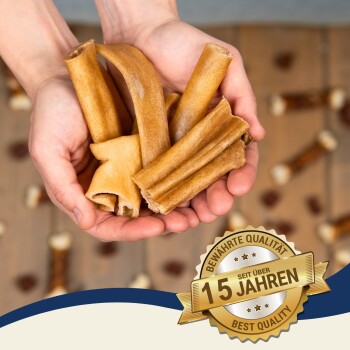 Ein Paar Hände hält verschiedene Hundekauartikel, einschließlich gerollter und flacher Leckereien, mit einem Abzeichen, das 'Beste Qualität seit über 15 Jahren' besagt.