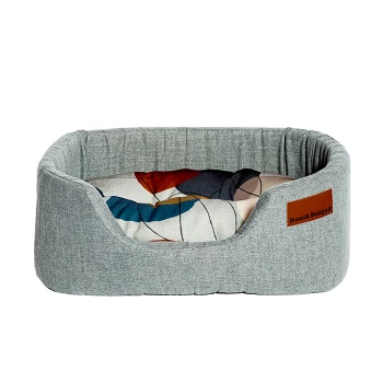 Graues Haustierbett mit einem bunten gemusterten Kissen, mit einem Lederschild, das 'Danish Design' liest.