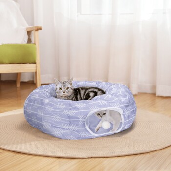 Ein gemütliches blaues Haustierbett mit weißen Pfeilmustern, mit einer entspannten getigerten Katze darin und einem verspielten Kätzchen, das von einer Seitenöffnung herauslugt.