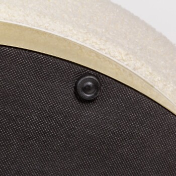 Nahaufnahme eines Haustierbettes mit einer weichen, cremefarbenen Oberseite und einem strukturierten schwarzen Boden mit goldener Kante und einem schwarzen Knopfdetail.